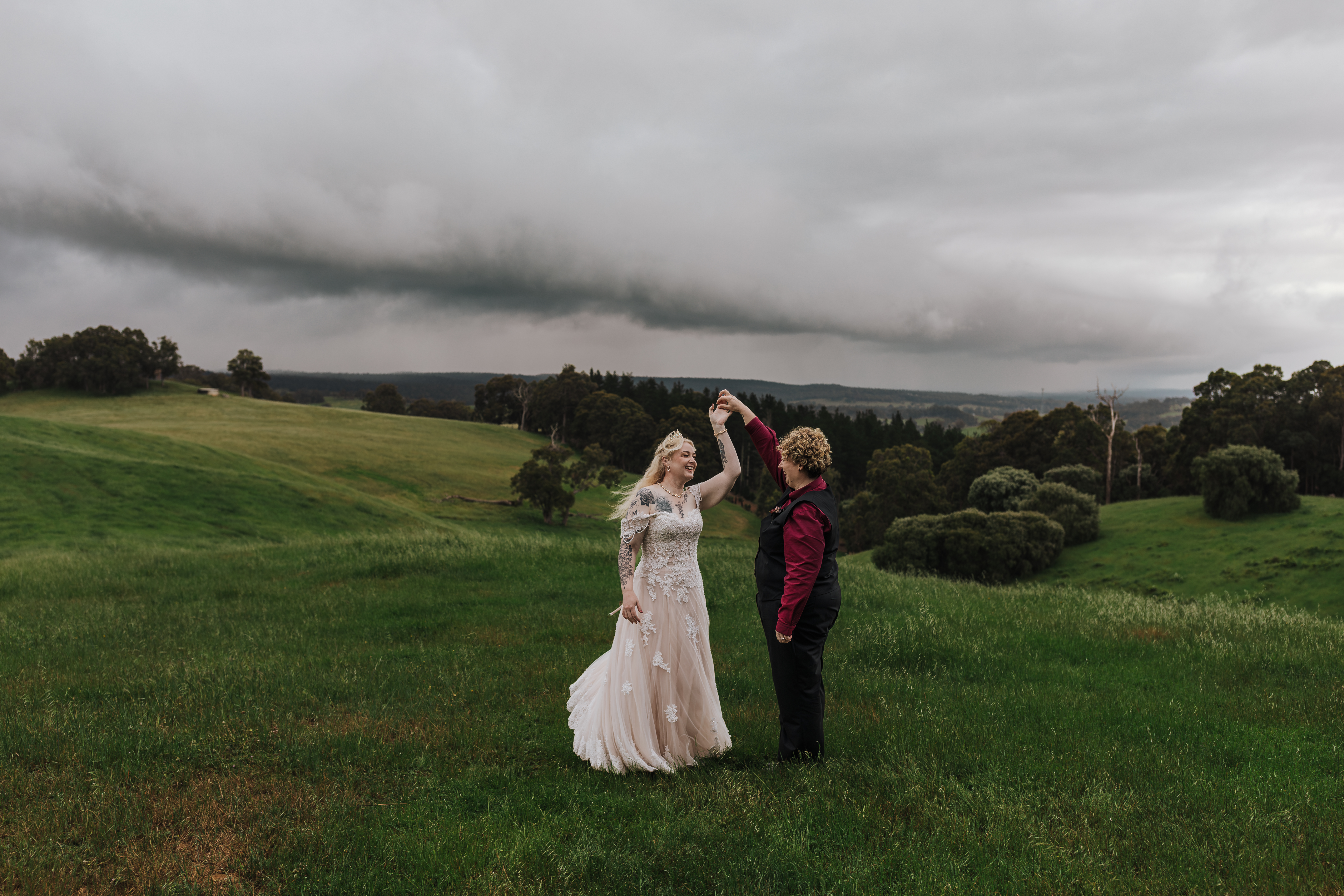 brides dancing together in the storm on a hill at Twelve Pillars wedding